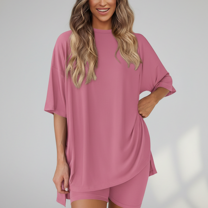 Woman wearing a pink oversized t-shirt and shorts set on a white background